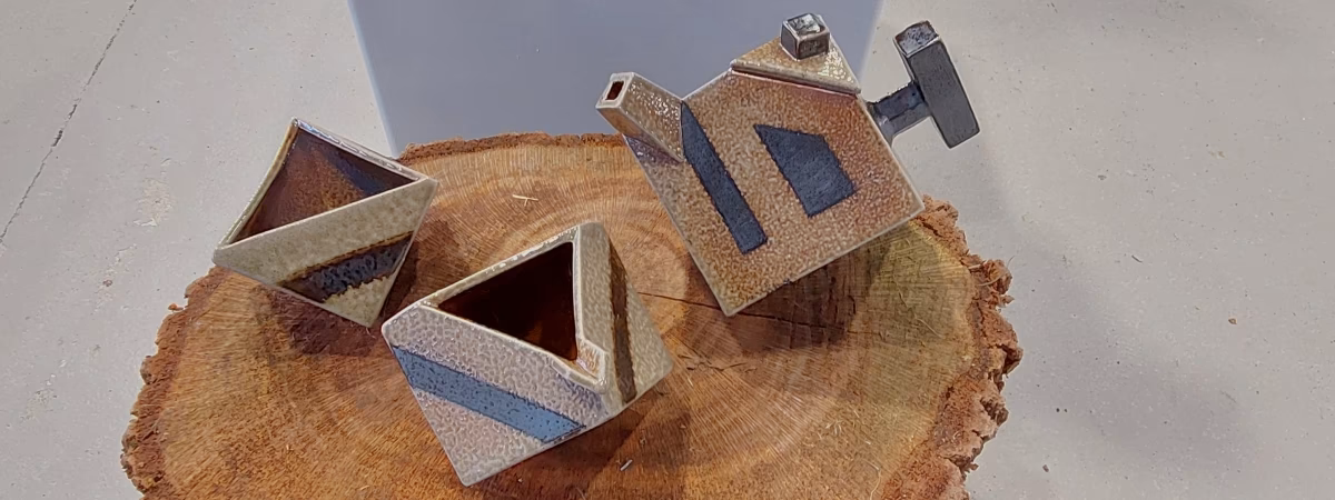 A geometric Fredrock Ceramics teapot and two triangular cups in a speckled brown glaze